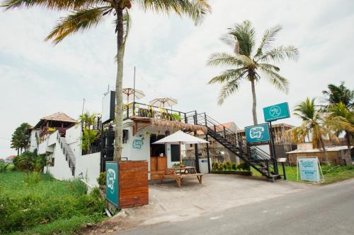 a building with palm trees on the side of the road at Swell Hotel, Pool Bar & Restaurant in Tanah Lot