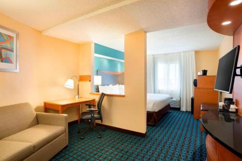 a hotel room with a couch and a bed and a desk at Fairfield Inn & Suites by Marriott Dallas Plano in Plano