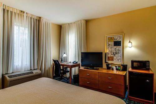 a hotel room with a bed and a desk with a television at Fairfield Inn & Suites Palm Coast I-95 in Palm Coast