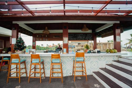 a bar with four orange bar stools in a restaurant at Swell Hotel, Pool Bar & Restaurant in Tanah Lot