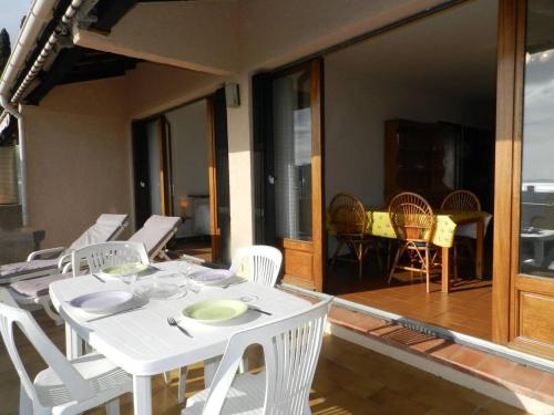 - une table à manger blanche et des chaises sur une terrasse couverte dans l'établissement Appt 2 pièces, terrasse 45m², parking, animaux acceptés - FR-1-251-855, à Bormes-les-Mimosas