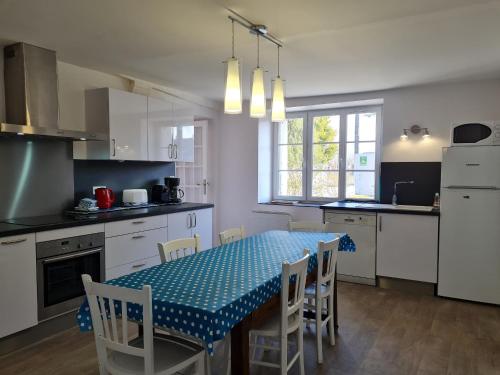 une cuisine avec une table et des chaises et une cuisine avec des armoires blanches dans l'établissement Gîte moderne avec jardin, terrasse et parking privé - FR-1-590-538, à Saint-Sigismond