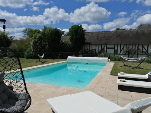 a swimming pool with two chairs in front of a house at Évasion Sologne : Maison de charme, piscine privée, animaux permis - FR-1-590-556 in Isdes