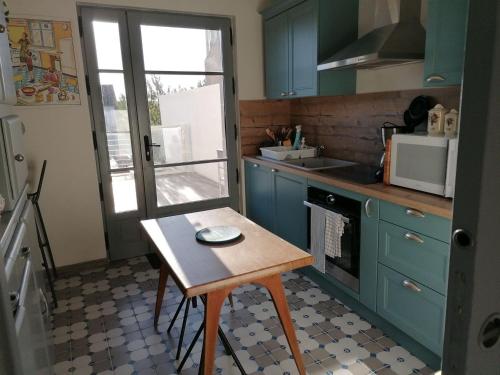 a kitchen with blue cabinets and a small table in it at Grand Gîte à Briare - Animaux et Parking Privé - FR-1-590-541 in Briare