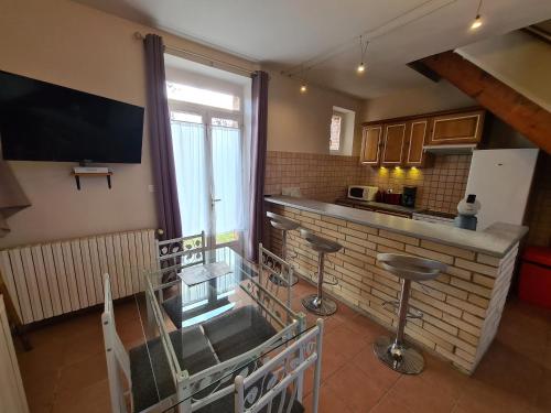 une cuisine avec une table en verre et une télévision murale dans l'établissement Charmant duplex avec parking et Wi-Fi près de Montargis - FR-1-590-546, à Lorcy