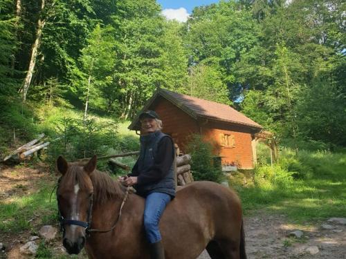 a woman riding a horse in front of a cabin at Yourte atypique avec sauna et terrasse privative - FR-1-589-765 in Ferdrupt