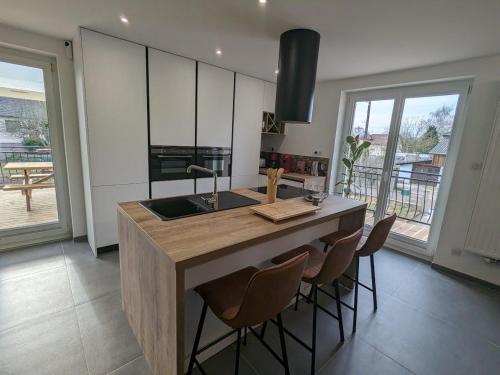 - une cuisine avec un îlot doté d'un évier et de quelques chaises dans l'établissement Gîte spacieux près du lac avec spa, aire de jeux, wifi et activités variées - FR-1-589-767, à Chaumousey