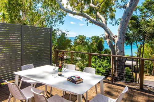 a table and chairs on a patio with a view of the ocean at Sunset Waters 15 & Free Buggy- Hamilton Island in Hamilton Island