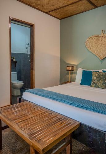 a bedroom with a bed and a bench in it at Golden Monkey Beach Hotel in El Nido