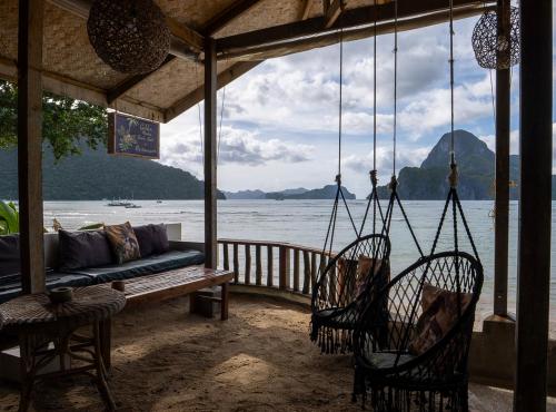 a porch with a couch and chairs and the water at Golden Monkey Beach Hotel in El Nido