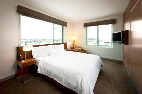 a hotel room with a large bed and two windows at Element Dallas Fort Worth Airport North in Irving