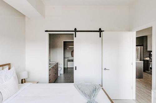 a bedroom with white walls and a bed with a chair at Contemporary Cool Lifestyle Loft - Zuni Lofts in Denver