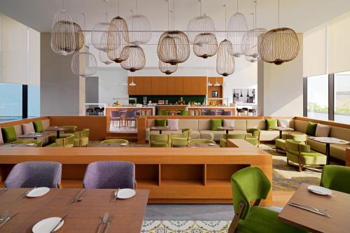 a restaurant with wooden tables and green chairs at Element Me'aisam, Dubai in Dubai