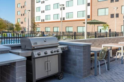 a grill on a patio with a table and a building at Element Dallas Richardson in Richardson