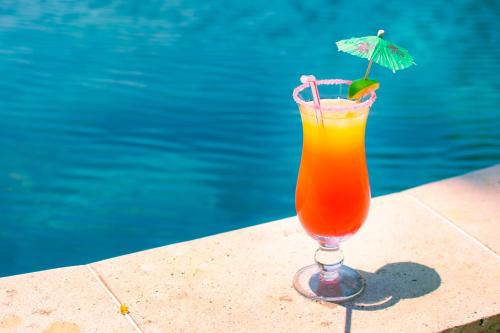 a drink with an umbrella sitting next to a pool at Ô Bleu Azur in Antsatrakolo