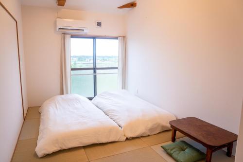 a bedroom with a bed and a table and a window at hostel ALA in Kawaminami