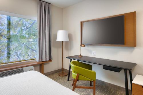 a hotel room with a desk and a television on the wall at Fairfield Inn & Suites by Marriott Denver West/Federal Center in Lakewood