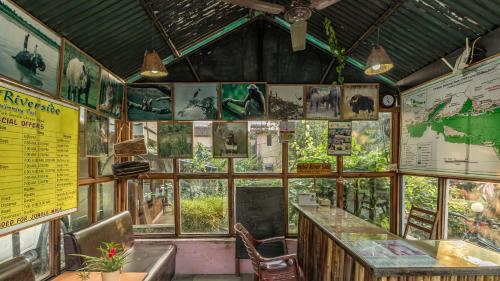 a restaurant with a bar and windows and signs at Hotel Riverside with Swimming pool in Sauraha