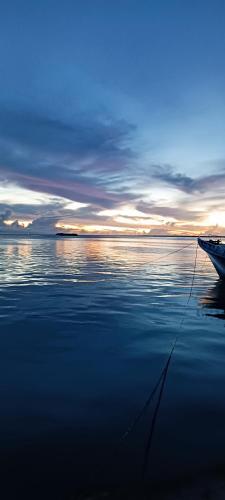 a boat is sitting on the water at sunset at Manta Sky Inn in Dharavandhoo