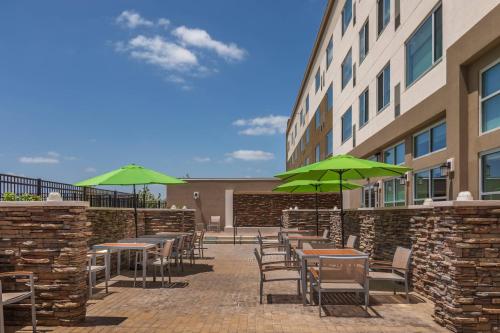 a patio with tables and chairs with green umbrellas at Element Houston Katy in Katy
