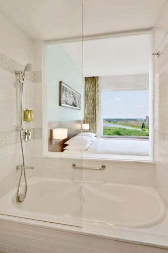 a bathroom with a tub and a bed and a window at Fairfield by Marriott Sriperumbudur in Sriperumbudur