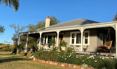 une maison blanche entourée d'une terrasse couverte. dans l'établissement Bylands Cottage Historic Home - Tambo river views and pet friendly, à Swan Reach