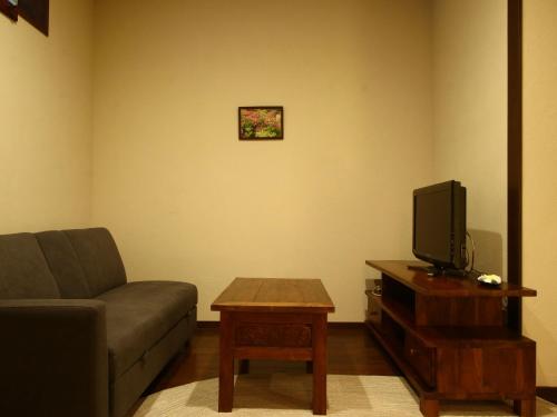 a living room with a couch and a tv at Hotel Bali Moon in Toi