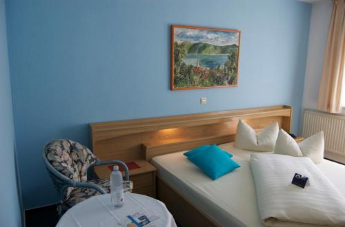 a room with two beds with a chair and a table at Hotel Karlshof in Karlsdorf-Neuthard