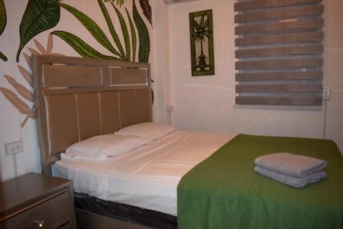 a small bedroom with a bed with a green blanket at VSS Tropical Oasis in Arecibo - Modern Comfort & Island Vibes in Arecibo