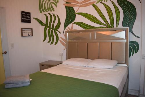 a bedroom with a bed with a plant mural on the wall at VSS Tropical Oasis in Arecibo - Modern Comfort & Island Vibes in Arecibo