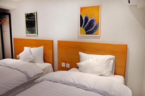 two beds in a hotel room with white pillows at The Avenue Hotel in Islamabad
