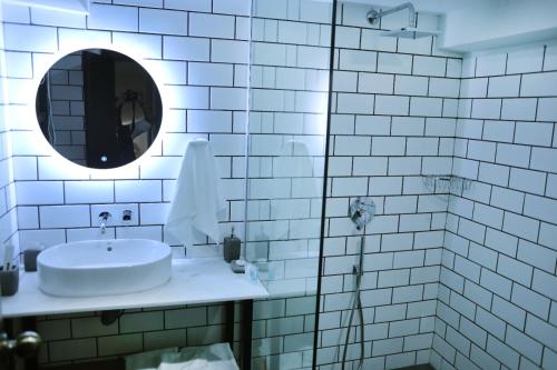 a white tiled bathroom with a sink and a mirror at The Avenue Hotel in Islamabad