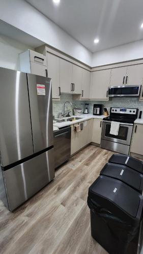 a kitchen with stainless steel appliances and white cabinets at Charming Oasis Tranquil Suite 8 min Airport, AC in Calgary