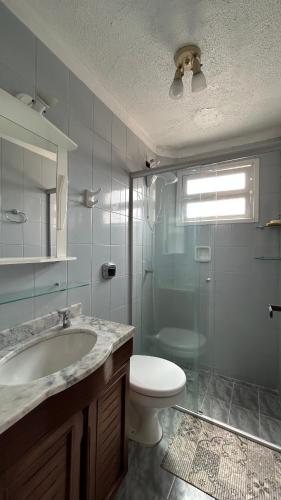 a bathroom with a toilet and a sink and a shower at Aconchegante apartamento 2 dormitórios no centro com vaga in Capão da Canoa