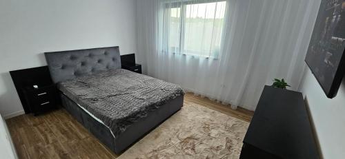 a bedroom with a bed and a large window at Dealul Viilor Residence in Drăgăşani