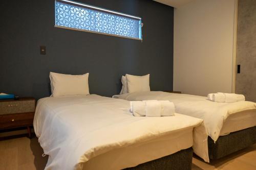 two twin beds in a room with a window at Koyo Onsen Chalet in Niseko