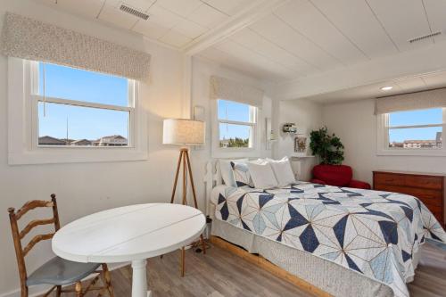 a bedroom with a bed and a table and windows at 4119 - The Dolphin Boat in Kitty Hawk