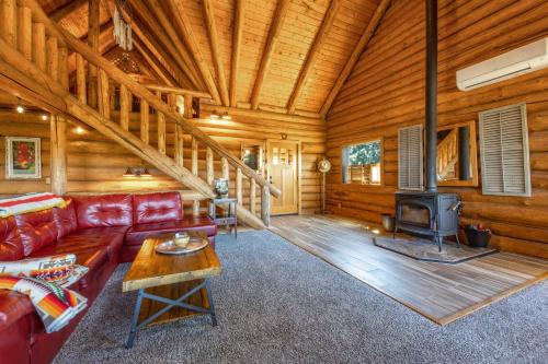 a living room with a red couch and a fireplace at Rowland Log Cabin in Lyle