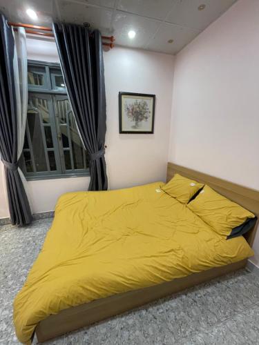 a yellow bed in a bedroom with a window at Home stay Thương Thương in Xuan An