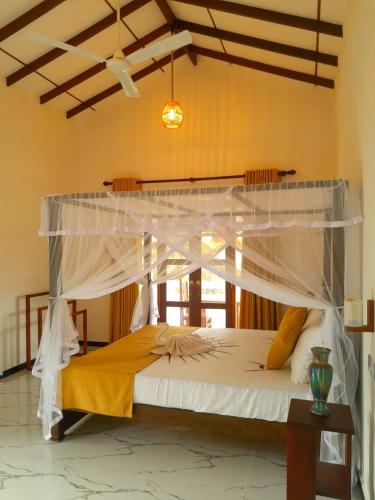 a bedroom with a large bed with a canopy at Serendib Villa in Ahangama