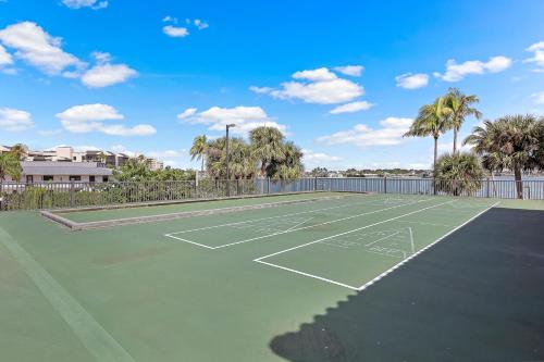 a tennis court with palm trees in the background at Breath-taking waterfront condo with pool/spa/tennis in Marco Island