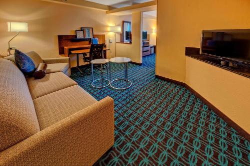 a hotel room with a couch and a table with a piano at Fairfield Inn and Suites by Marriott Orlando Near Universal Orlando in Orlando