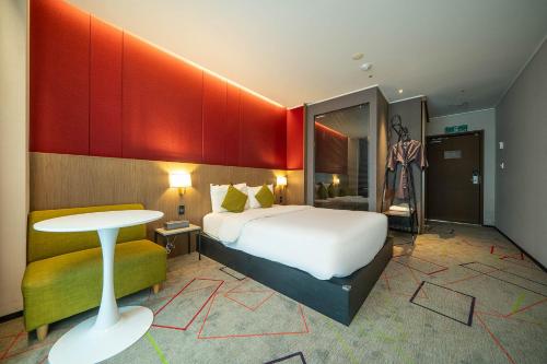 a bedroom with a bed and a table and a stool at South Vandeco Hotel in Busan