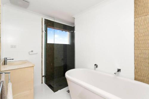 a bathroom with a tub and a glass shower at Relaxing Getaway Beachfront Access Multi Family Pets Mandurah in Mandurah