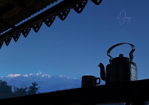 a tea kettle sitting on a window sill with mountains in the background at Meghpiyon Homestay in Pedong
