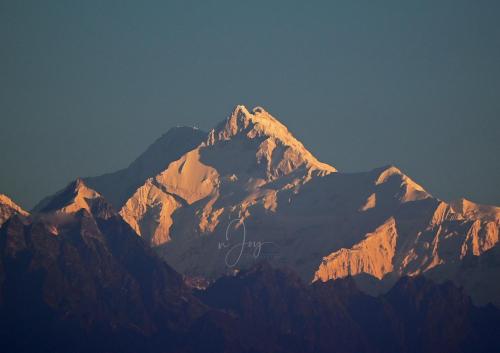 a view of a mountain range with the sun shining on it at Meghpiyon Homestay in Pedong