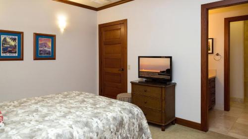 a bedroom with a bed and a television on a dresser at Villages At Mauna Lani 621 in Waikoloa