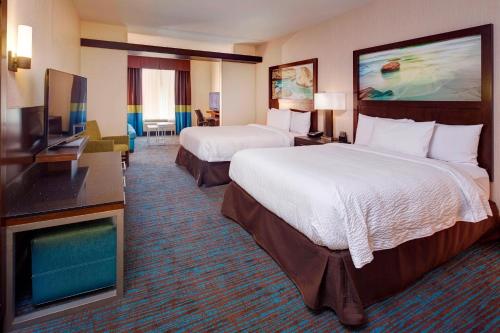 a hotel room with two beds and a flat screen tv at Fairfield Inn & Suites by Marriott San Diego Carlsbad in Carlsbad