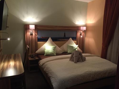a bedroom with a bed with a stuffed animal on it at Hotel Meereswoge in Cuxhaven