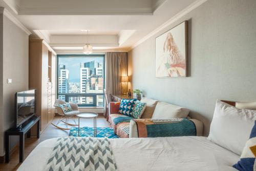 a room with a bed and a couch and a window at Artistic Studio in Taichung